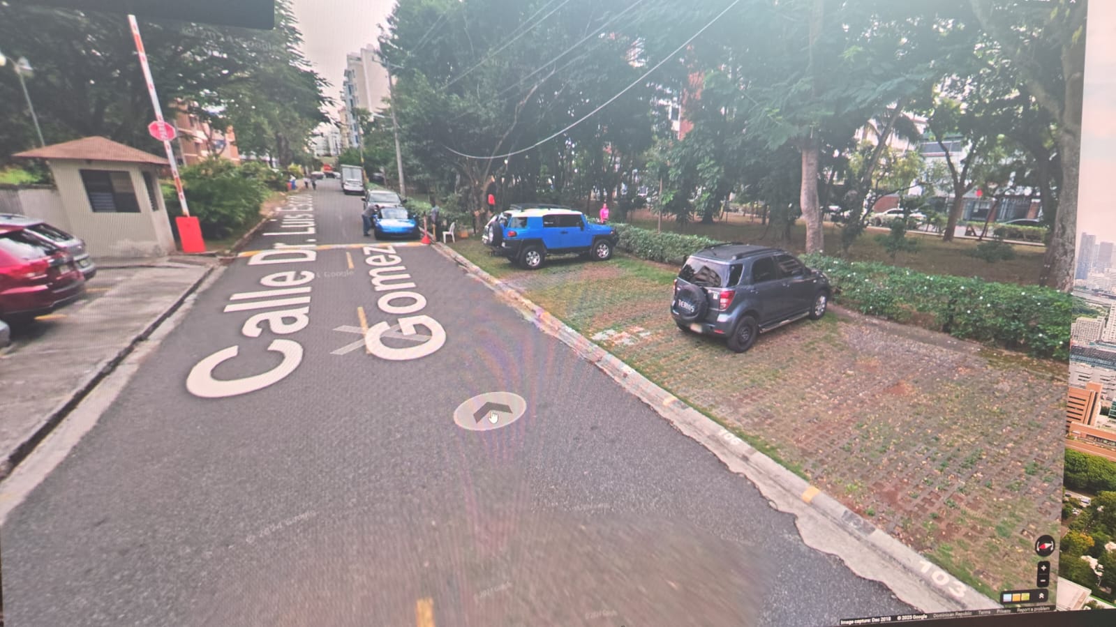 Garita con brazo levantado junto a la calle y parqueos del perímetro del bosque